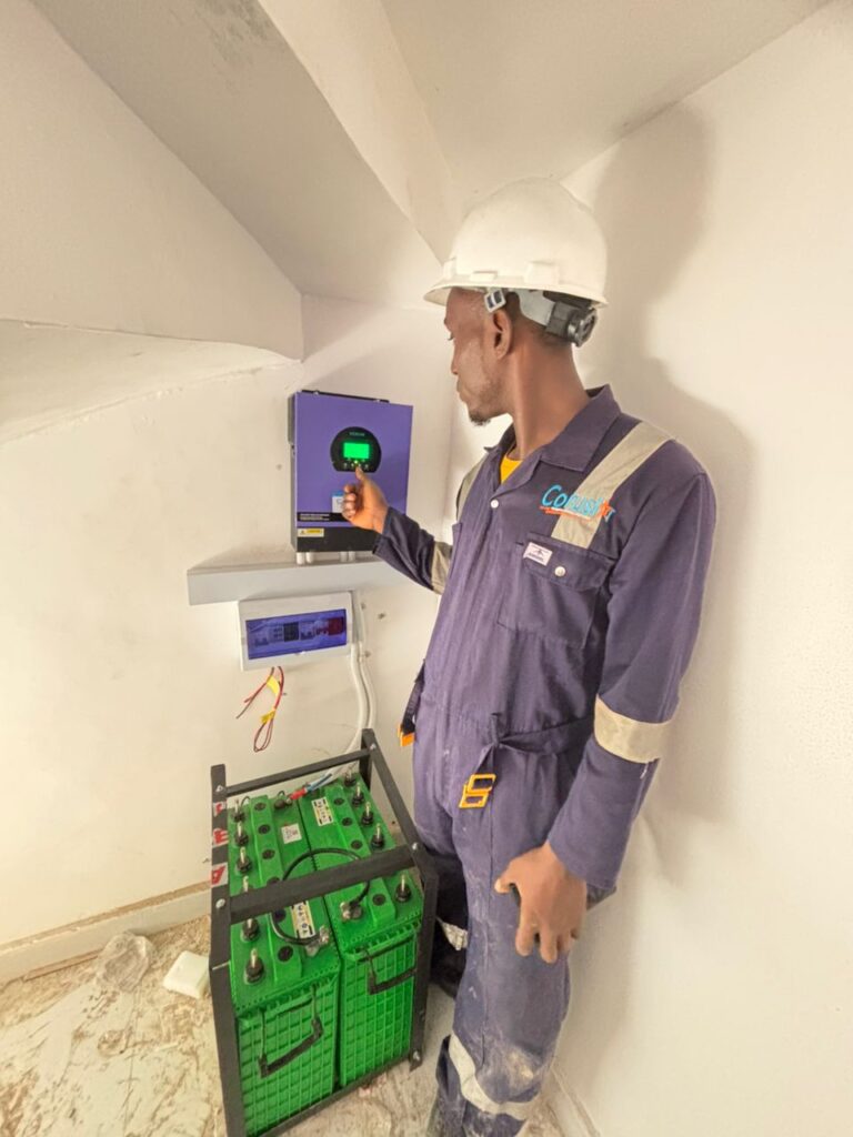 Technician beside an inverter and battery bank installation